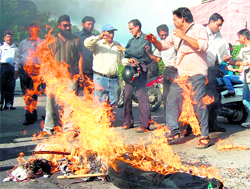 Members of the Uttarakhand School Van Association burn an effigy of the Central Government in protest against the petrol price hike as the clothes of one of the members catch fire in Dehradun on Friday