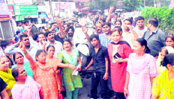 BJP Mahila Morcha members hold a demonstration carrying a scooter on a cart