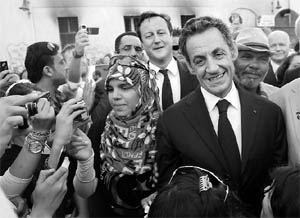 Frances President Nicolas Sarkozy (R) and Britains Prime Minister David Cameron (rear, centre) meet local people in Benghazi on September 15, 2011. Cameron said his government would look to unfreeze a further 12 billion in Libyan assets if a United Nations Security Council resolution on Libya was passed.