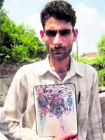Vijay Kumar with a photograph of his relatives who died in a counter-insurgency operation.