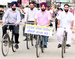Patiala Mayor Ajit Pal Singh Kohli (supporting a placard) on a bicycle to protest against the hike in petrol price in Patiala on Friday