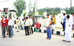 Commuters wait for a bus in the open near Rajiv Chowk in Rohtak