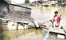 A man retrieves belongings from his submerged hut along the banks of the Jhelum in Srinagar on Saturday. 