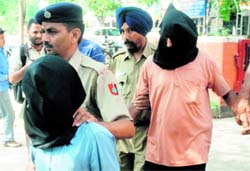 Raju Singh Yadav and Budh Ram, accused of murdering a guard, being led out of the Industrial Area police station in Phase I, Chandigarh, on Sunday