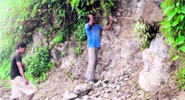 A labourer digs out a boulder from a mountain illegally to use it in the construction of barriers on the road.