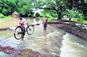 People wade through a flooded road at Tipuri village of Orissa on Sunday. 