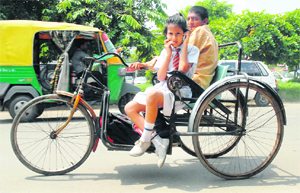 A polio-afflicted man takes his daughter to school on his tricycle in Chandigarh on Monday.