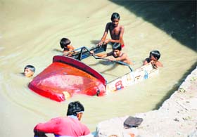 Children lend a helping hand after a three-wheeler fell into a canal in Faridabad. 