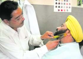 A man gets his beard trimmed at a barber’s shop in Mandi Ahmedgarh