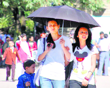 Girls use an umbrella on a sunny day in Shimla on Tuesday