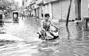 A motorcyclist wades through a waterlogged road in Khetan Market after heavy downpour in Patna on Tuesday. 