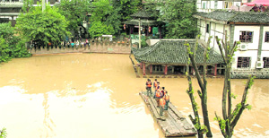 Members of a rescue team stand on a raft as they search for survivors in a flooded area in China on Tuesday. Nineteen persons were killed and over three million hit in flooding and landslides in the country