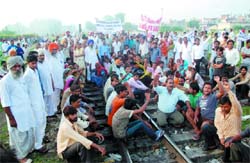 Protesters squat on the railway track near the Patiala crossing on Wednesday. They were demanding the laying of sewerage pipes in their localities. 