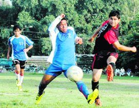 Players of XI Star Club (in blue) and Doon Valley Club (in red) vie for the ball in a match in the Doon Callisto Cup tournament in Dehradun on Wednesday