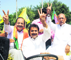 Kuldeep Bishnoi, HJC-BJP nominee, flashes the victory sign as he arrives at the mini-secretariat in Hisar to file his nomination on Wednesday. He is flanked by BJP leader Harshvardhan (left) and former MP Dharam Pal Malik (right).