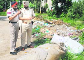 Police officials inspect the bags containing bio-medical waste that were found dumped by a pharma unit in an open area on the Garha road in Jalandhar on Wednesday