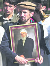 A supporter of Burhanuddin Rabbani holds a picture of him while standing outside his house in Kabul on Wednesday