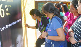A girl signs a board during a campaign on the Daughters Day in New Delhi 