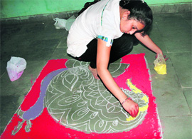 A girl participates in a rangoli competition at the University of Jammu on Friday. 