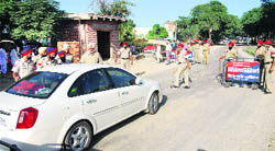Police personnel check a car on the eve of farmers' protest in Gobindpura village of Mansa district.