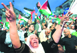 Palestinians wave flags before a public screening of Palestinian President Mahmoud Abbas speech at the UN, in the West Bank city of Ramallah on Friday