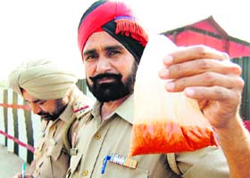 A police personnel shows a pouch containing red chilli powder used in the crime