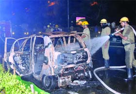 A fireman douses flames after a Nano car caught fire outside the PHQ in New Delhi on Sunday evening