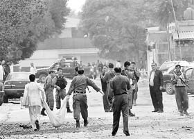 Security personnel carrying the body of a terrorist involved in the suicide bomb attack at the US Embassy in Kabul on September 13
