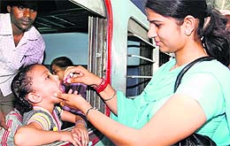 A contractual multipurpose health worker administers polio drops to a child in a train at the railway station in Jalandhar on Sunday. Tribune photo: Sarabjit Singh