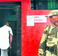 A paramilitary official stands guard at the entrance of a voting booth as a man enters during a bypoll in Kolkata on Sunday.