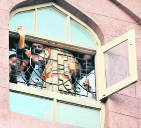 A policeman stops members of Telangana Advocates Joint Action Committee from shouting slogans from a window during their protest at the Hyderabad High Court on Monday. 