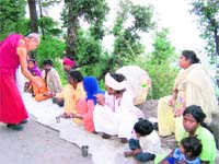 A monk gives alms to beggars in McLeodganj. 