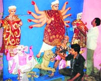 Kamal Paul, an artist from West Bengal, along with a co-artist, gives finishing touches to the idol of Mahishasur Mardini in Kangra.