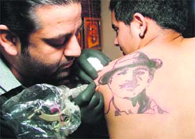 Nick Sharma, an artist, makes a tattoo of Shaheed Bhagat Singh on the shoulder of a youngster in Ludhiana on Tuesday