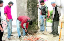 Municipal Council employees demolish a wall constructed illegally in Mussoorie on Friday.