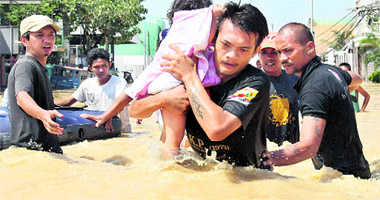Volunteers help residents to cross a flooded area as they evacuate to safer grounds in Calumpit township, Bulacan province, near Manila on Friday.
