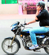 A motorcyclist is unmindful of traffic rules as he talks on his mobile phone while riding a bike in Amritsar