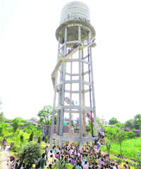NRHM employees climb atop a water tank at Gill village. 