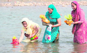 Devotees immerse Saankh, holy grass, in the Tawi on the occasion of Mahanavami in Jammu 