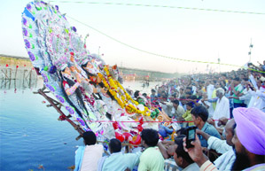 Devotees immerse an idol of Goddess Durga in the Yamuna at the end of Durga Puja festival in New Delhi on Thursday.