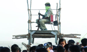 A policeman keeps a vigil at the crowd during the immersion of idols of Goddess Durga in the Yamuna in New Delhi on Thursday. 