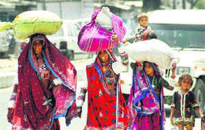 Women dressed in traditional outfits on a busy road in Gurgaon. 