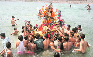 Devotees immerse an idol of Goddess Durga in the Tawi in Jammu on Thursday. 