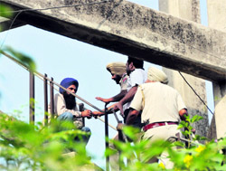 Police personnel try to convince an NRHM employee sitting atop a water tank to end stir