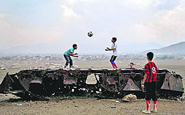 Afghan boys play with a ball on top of the remains of a Russian armoured vehicle in Kabul, Afghanistan, on Thursday
