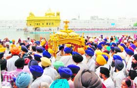 Sikh devotees carrying the palanquin in the Nagar Kirtan procession on the eve of the birth anniversary of the fourth Sikh guru, Guru Ramdass, in Amritsar on Saturday
