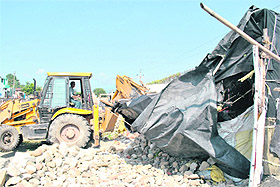 A bulldozer of the Dehradun Municipal Corporation removes an illegal structure in Bhagat Singh Colony in Dehradun on Monday.