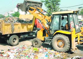 Garbage being lifted by a JCB machine from a dump near Ladowali Road in Jalandhar on Monday