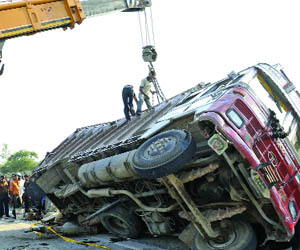 Labourers working with a recovery crane to pull out a truck on Outer Ring Road near Old Bridge in New Delhi on Tuesday. 