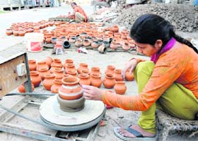 A girl colours pots for the upcoming Karwa Chauth festival in Karnal
